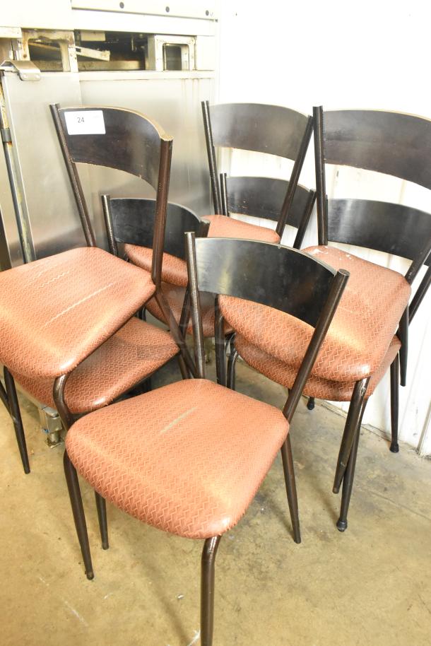 Set of 7 dining height chairs with orange/brown seat cushions, black frames, light wear. Auction tag visible.