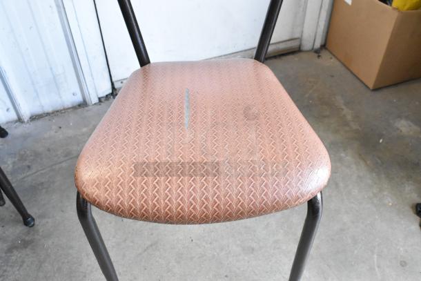 Dining chair with orange-brown seat cushion, metal legs, minor wear on cushion, industrial style.