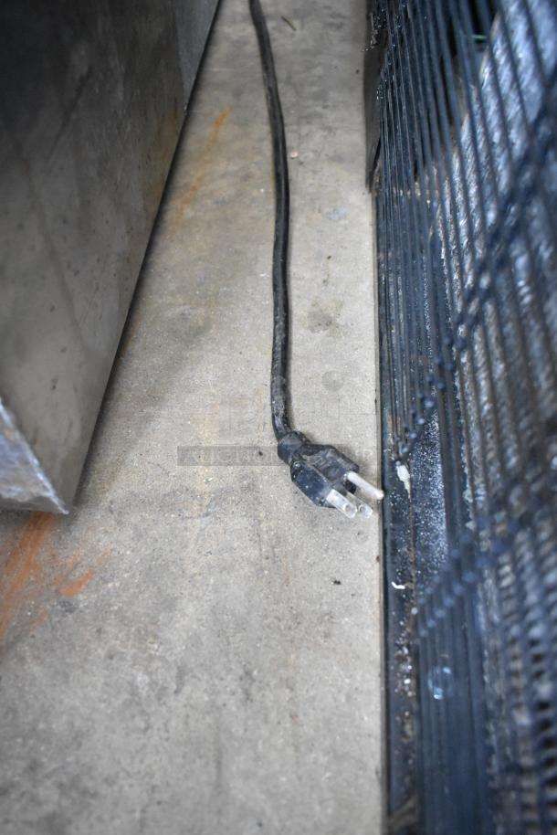 Turbo Air TD-5R deli display case power cord, 115V, 1 phase, resting on concrete near metal and fenced surfaces.