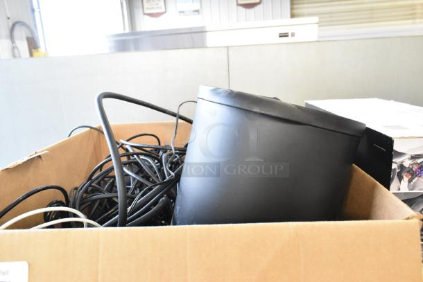 Box of mixed electronics including cables, a black container, and a box. Contains credit card readers, queuing discs, hard drive.
