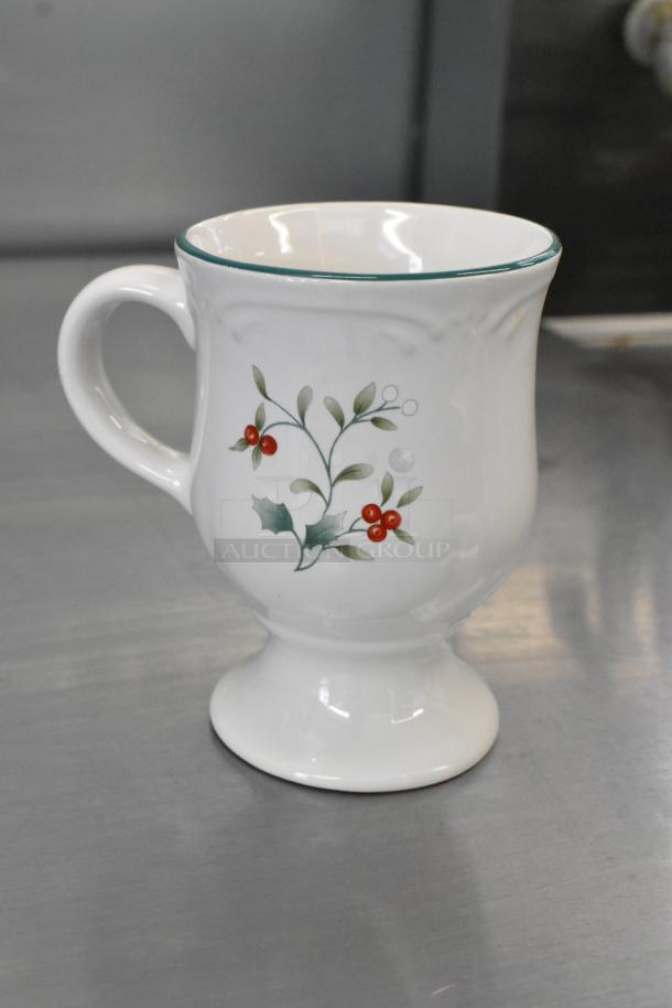 White ceramic footed mug with green trim and holly berry design, in excellent condition. Part of a set of three.