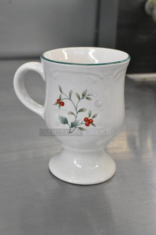 White ceramic footed mug with green trim and holly berry design, in excellent condition. Part of a set of three.