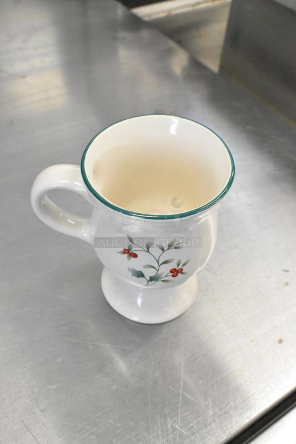 White ceramic footed mug with green rim and holly design, in excellent condition. Part of auction set of three.