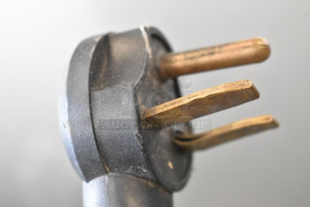 Close-up of a three-prong plug for a Turbochef NGC electric rapid cook oven, showing wear on metal prongs.