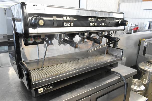 Dalla Corte stainless steel 3 group espresso machine with 3 portafilters, 2 steam wands, and control panel, in good condition.