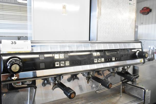 Dalla Corte stainless steel 3 group commercial espresso machine with 3 portafilters, 2 steam wands, and control panel.