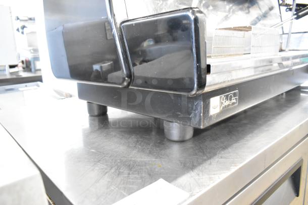 Dalla Corte 3-group stainless steel espresso machine with 3 portafilters, 2 steam wands, and brand logo on side panel.