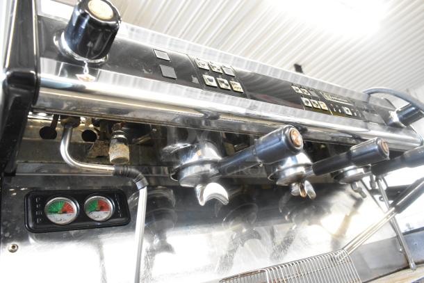 Dalla Corte stainless steel 3 group commercial espresso machine with 3 portafilters, 2 steam wands, and dual gauges.
