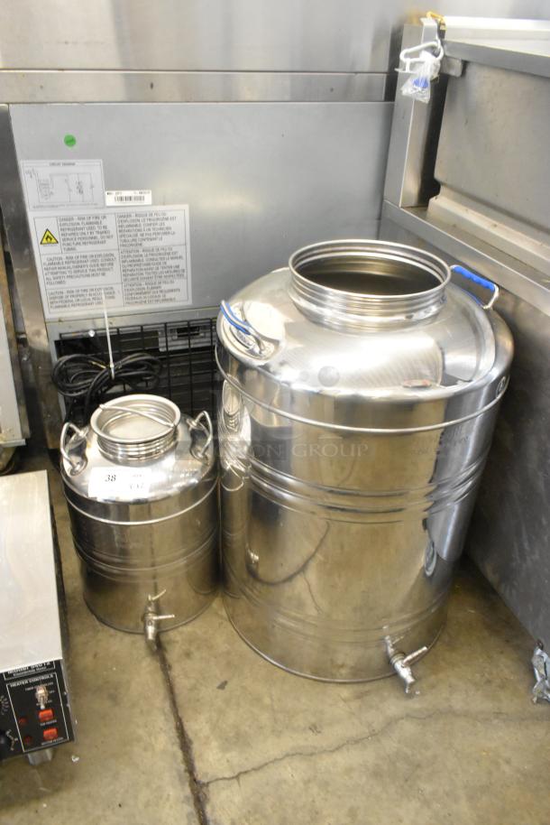 Two shiny metal urns with spouts, different sizes. Larger urn has a blue handle. Both appear in good condition.