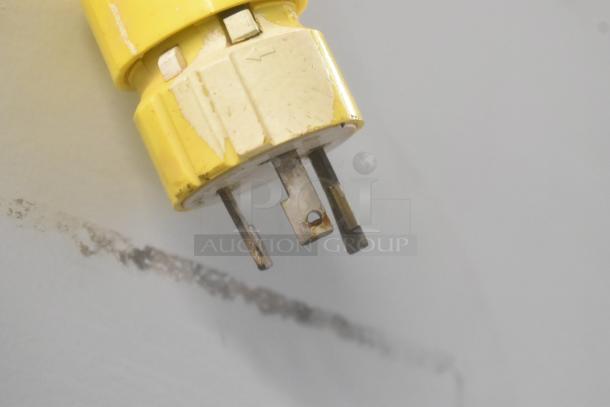 A yellow electrical plug, showing signs of wear, with metal prongs, part of Thermo 3920 Chamber Incubator power setup.