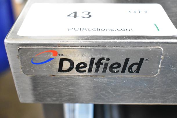 Delfield UCD4464N-12-DD5 stainless steel commercial prep table with 4 drawers, over-shelf, and visible logo tag.