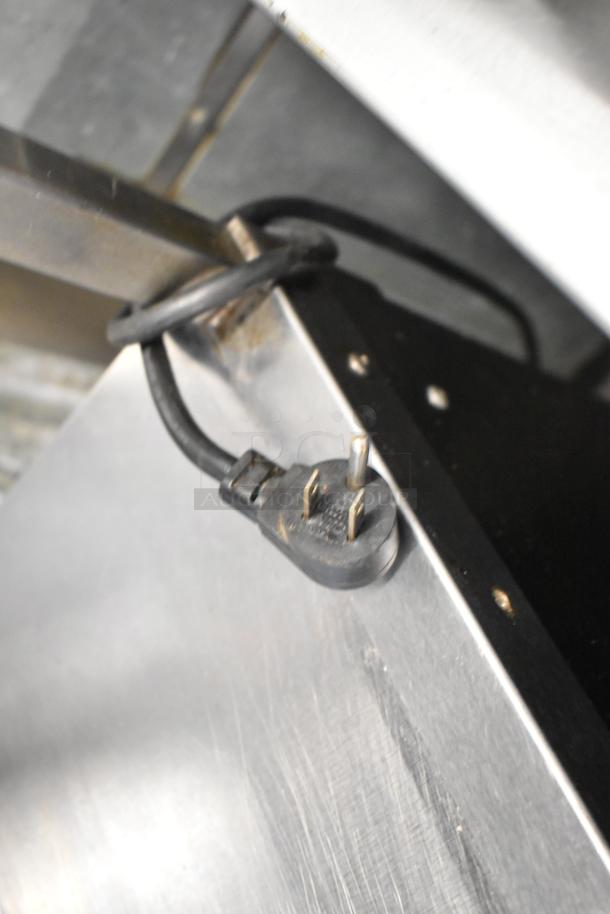 Close-up of a power plug connected to a Delfield UCD4464N-12-DD5 stainless steel prep table, showing detail of electrical connection.