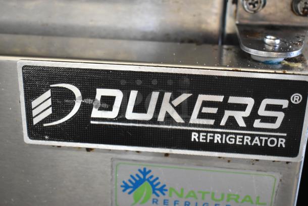 Dukers DSP60 stainless steel prep table label, indicating brand and model. Features include refrigeration and commercial casters.