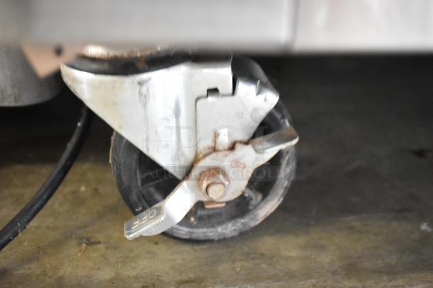 Close-up of a caster wheel with a brake mechanism on the Summit ARS49ML commercial cooler.