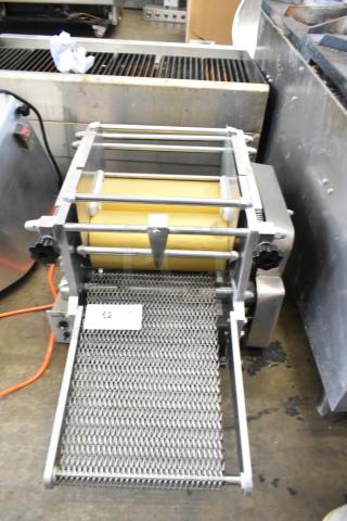 Metal countertop sheeter with yellow rollers and metal mesh conveyor, used condition, visible control knobs and power cord.