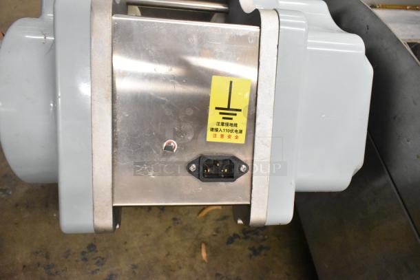Metal Commercial Countertop Sheeter with a power plug, safety label in foreign text, and visible metal casing.