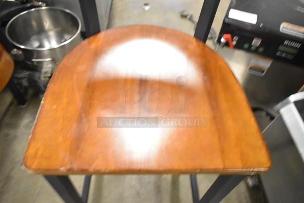 Four black metal bar-height chairs with wooden backrests and seats, showing minor wear. Industrial style, sturdy design.
