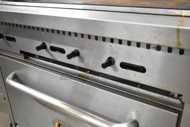 Cooking Performance Group 351S36G36N stainless steel flat top griddle with oven, over shelf, backsplash, and commercial casters.
