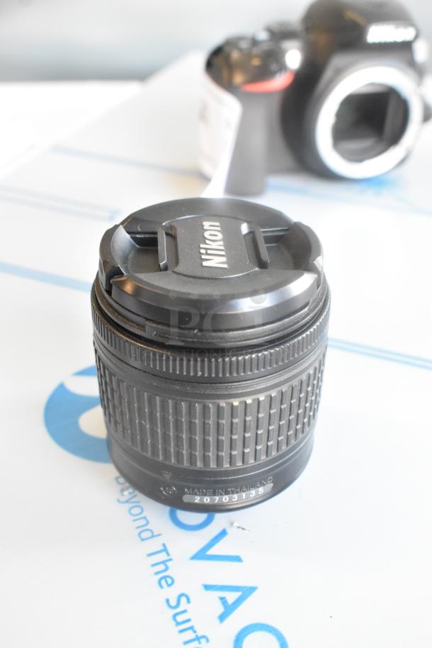 Nikon AF-P Nikkor 18-55mm f/3.5-5.6G lens with Nikon cap, mint condition, next to Nikon D3500 camera body.
