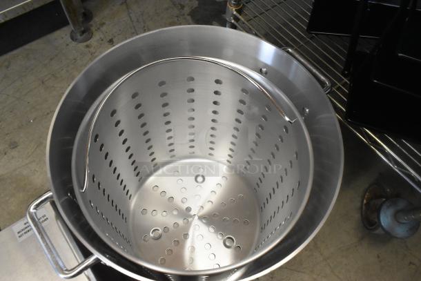 Brand new 16 15/16" aluminum stock pot with dent, includes pan cover. Handle details and perforated design visible.