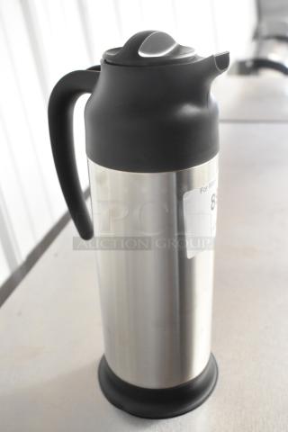 Stainless steel Choice pitcher with black handle and lid, visible scratch and dent, new condition with label attached.