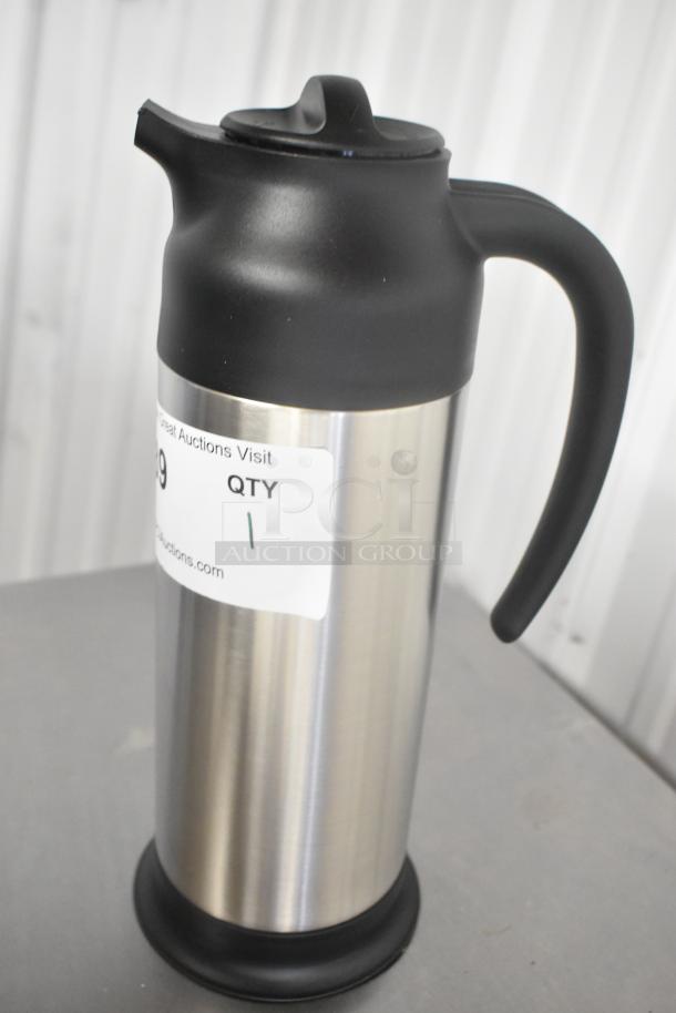 Stainless steel pitcher with black plastic lid and handle, marked "QTY 1" on label. New with minor scratches.