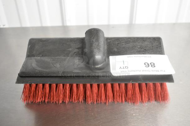 Brand new scratch and dent red-bristled broom head with black plastic base, slight blemishes visible, auction tag reads "QTY 1 86".