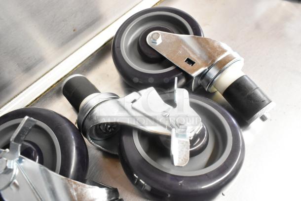Lot of 4 new commercial casters, scratch and dent condition. Features metal brackets and black rubber wheels.