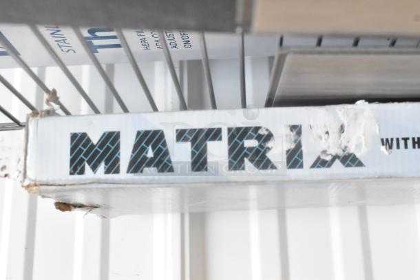 Three boxes of Matrix Flooring, brand new with scratch and dent packaging, showcasing dark geometric text and visible wear.