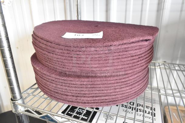 Stack of 20 maroon floor scrubber pads on metal shelf, labeled "103," indicating auction lot number.