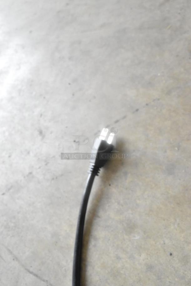 Power cord for Lavex Pro Hand Dryers on concrete floor, focus on plug end.