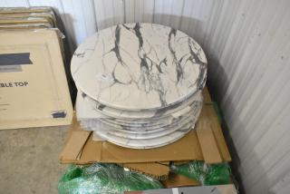11 brand new round marble pattern tabletops, scratch and dent condition, stacked on cardboard with visible tags.