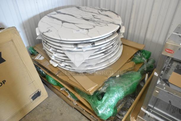 Stack of 11 brand new round marble pattern tabletops with minor scratches and dents, packed in cardboard.