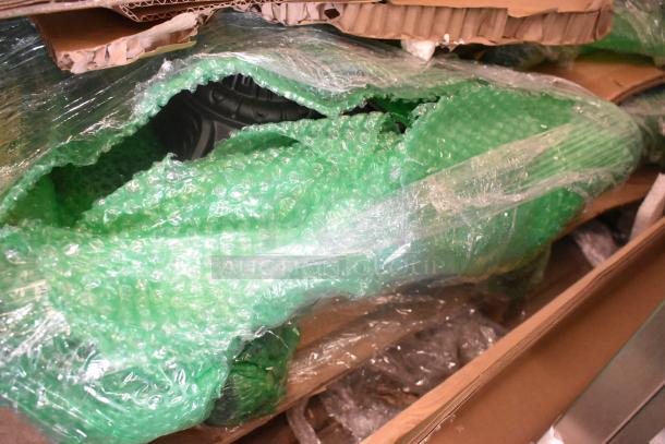11 new scratch and dent items, wrapped in green bubble wrap, including a round marble pattern tabletop.