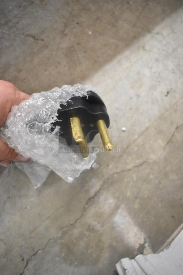 Electrical plug of the Avantco 177STE4SA Steam Table, partially wrapped in bubble wrap, showing gold prongs.