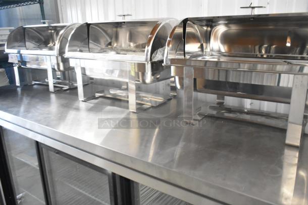 Three new stainless steel chafers with minor scratches, polished finish, sturdy legs, reflective surfaces.