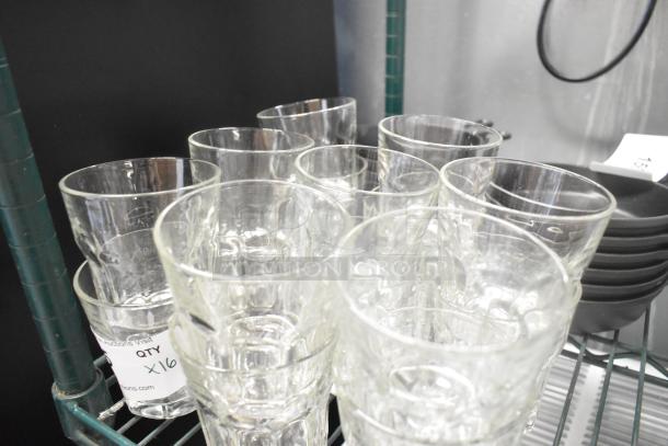 16 brand new scratch and dent beverage glasses on a metal shelf, labeled "QTY X16."