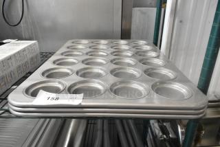 Three brand new 24-cup metal muffin pans, labeled "Scratch and Dent," stacked on a shelf, auction tag visible.
