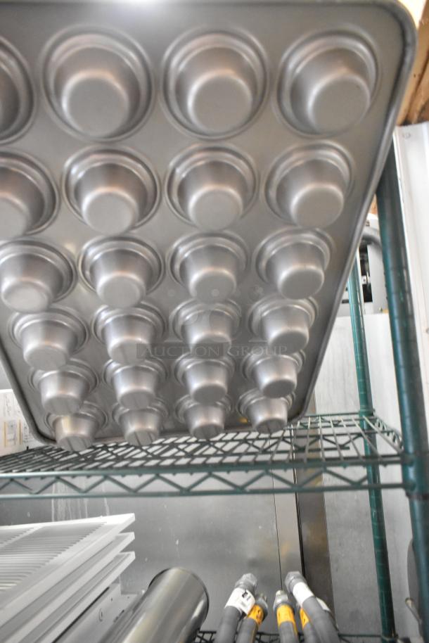 3 new metal 24-cup muffin pans, scratch and dent condition, stacked on a shelf. Multiples included with bid.