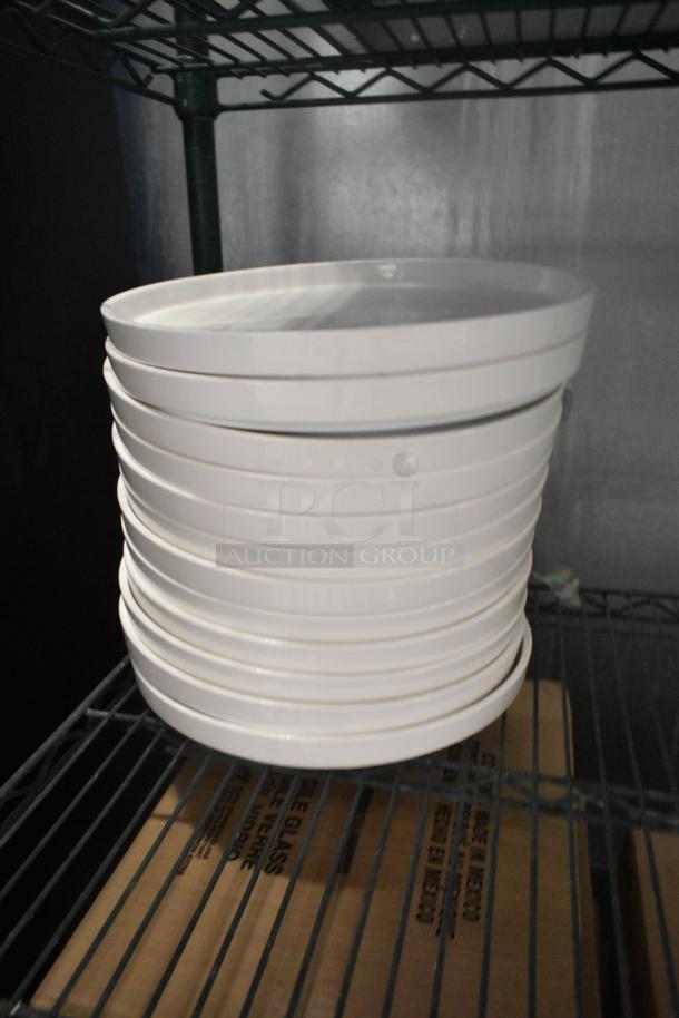 12 Acopa white plates, brand new scratch and dent, stacked on a metal shelf, cardboard box visible below.