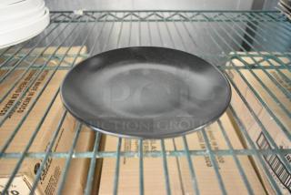 Acopa black plate on a shelf, brand new scratch and dent, part of a set of 36 for auction.