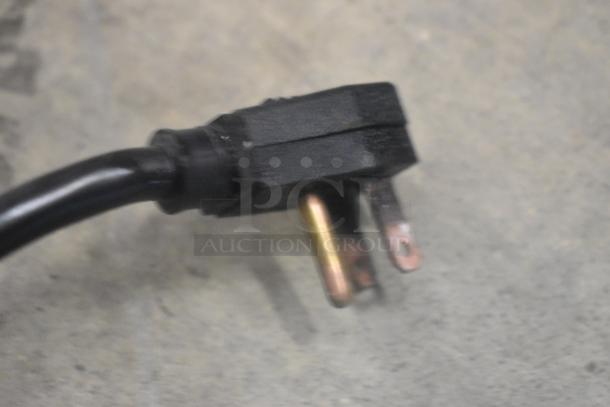 Close-up of a power plug for the True T-23F commercial freezer, showing three prongs and a black casing.