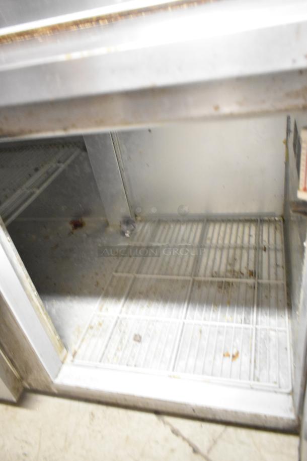 Beverage Air DP67 stainless steel commercial pizza prep table interior, showing shelving and storage space. In used condition.