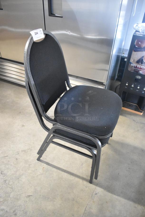 Two brand new black metal stackable banquet chairs, scratch and dent condition, shown stacked. Auction tag reads "204 QTY 2."