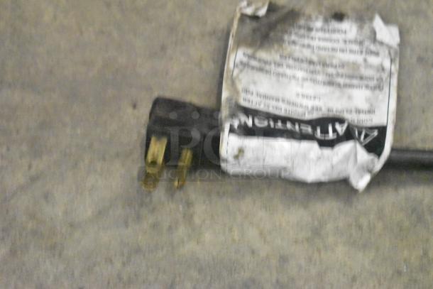 Black power plug with attached worn label showing instructions.