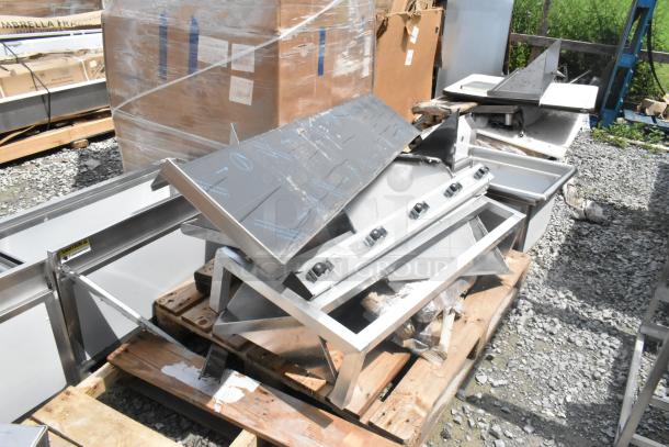10 brand new scratch and dent items including Regency stainless steel racks and leg, on wooden pallets outdoors.