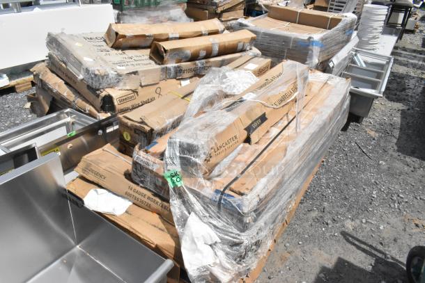 Stack of boxed restaurant equipment including Regency stainless steel work table and Steelton chrome shelf kit, all new.
