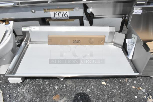 Brand new Regency 600CDT60L 16 Gauge 5' clean dish table with left drainboard, visible tape, slight scratch, suggests handling marks.