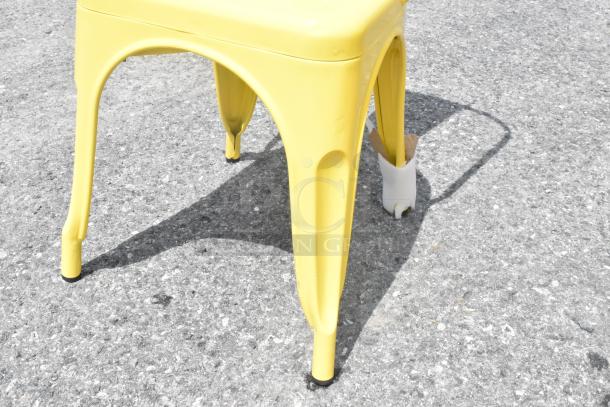 Yellow metal Tolix style chair, new condition, minor scratches, visible protective wrap on leg.