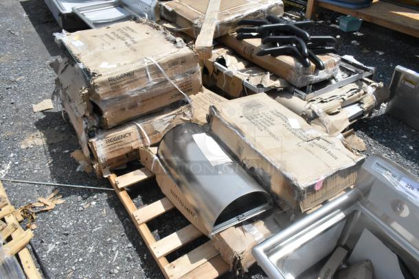 7 brand new scratch and dent items including seat cushions, stainless tables, and racks on pallets. Boxes marked "Regency."
